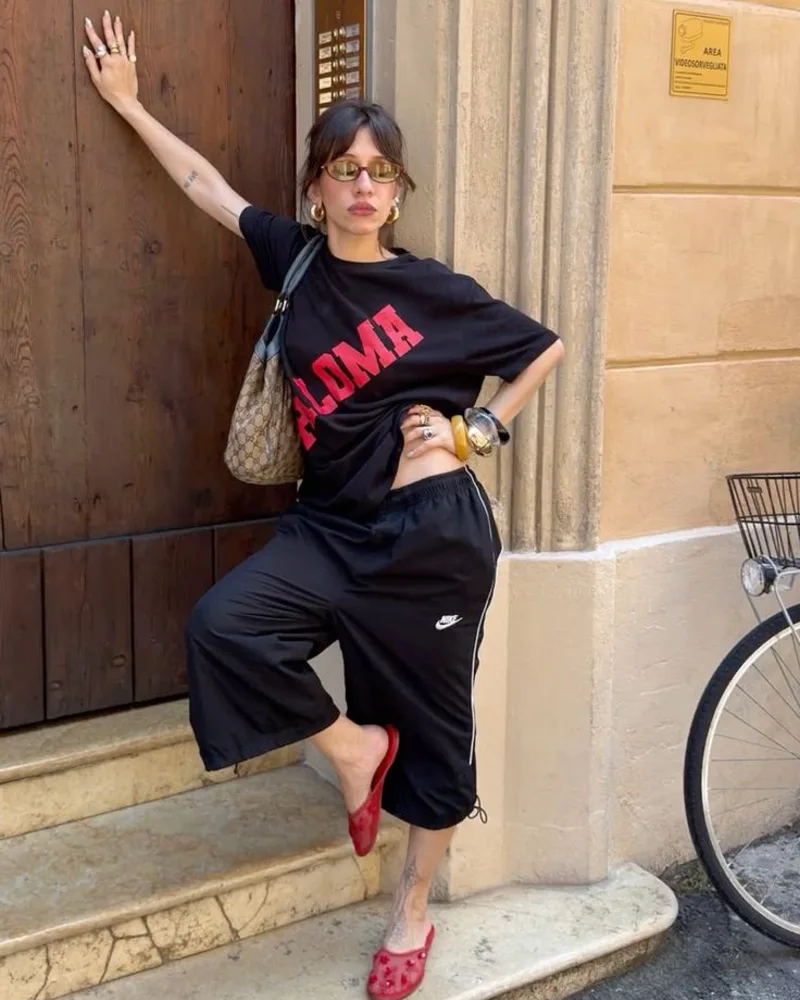  All-Black Graphic Tee and Nike Track Pants with Red Flats